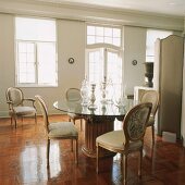 Elegantes Esszimmer mit Säulenglastisch und barocken Stühlen
