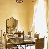 Marokkanischer Esstisch mit mosaikbefliester Platte und Stühle aus Metall und Bast