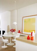 weiße Esszimmergarnitur im Retrostil vor einem gelben Gemälde im hellen, modernen Esszimmer