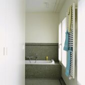 Mosaikfliesen ziehen sich vom Boden über die Badewanne bis zur Wand und werten das schlichte Badezimmer auf
