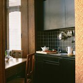 Gemütliche Küche mit antikem Esstisch im Erker und schwarz gefliester Küchenzeile