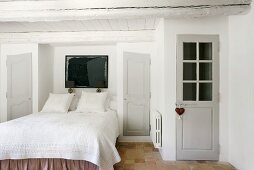 Das gemachte Bett im Schlafraum eines romantischen Bauernhauses