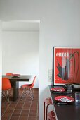 Rote Farbakzente an der gedeckten Küchentheke und dem minimalistischen Esstisch mit Designerstühlen