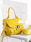Gelbe Handtasche und Zitronen auf einem Stuhl