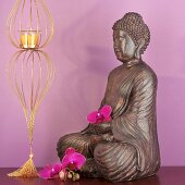 Buddhafigur mit Orchideen und Windlicht