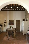 View through arches onto a dining area and tile floor of a Mediterranean country home