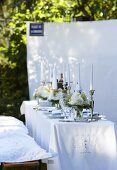 A white, elegantly laid table in a garden