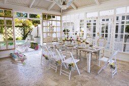 Festlich gedeckter Tisch mit Blumenschmuck in einem Wintergarten
