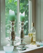 Candle holders and white wine on a window sill