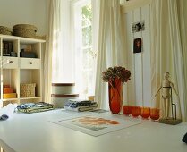 Baskets, table clothes, flower vases, a sculpture etc on a table