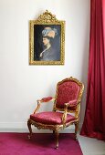 A baroque armchair with red upholstery underneath an oil painted in a gold frame