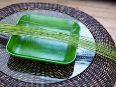 Green dish with ornamental grasses on a glass top of a rattan table