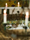 Blick durch gehängtem Kerzenleuchter auf Metalltisch mit Blumenvasen