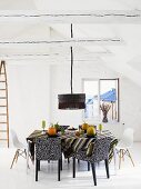 White attic with chairs in a mix of styles at a dining table and black hanging lamp