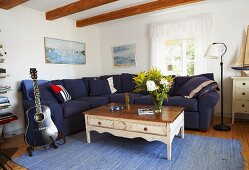 A living room in a country house - a blue guitar next to a white coffee table and a sofa