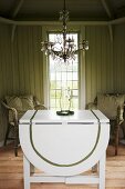 A white folding table with chairs and a chandelier in front of a window