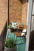 A sunny spot on a balcony in front of a brick facade with wooden chairs and pots of lavender