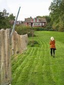 Aufgehängte Fischnetze im Garten und Frau mit Blick zum Holzhaus