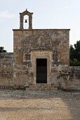 Romanische Kirche mit verwitterter Steinfassade und Glockenturm