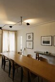Ceiling light with cantilevers above a long wood table and chairs in 50's style