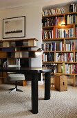 Schwarzer Tisch vor beleuchtetem Bücherregal in Wandnische und Wandboard im Fifties Stil