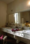 Dimly illuminated marble vanity with bathing items and a wall mirror