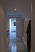 Narrow hallway with recessed spot lights and a white lacquer floor