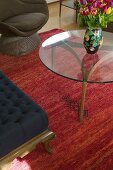 Glastisch mit buntem Tulpenstrauss auf rotem Teppich