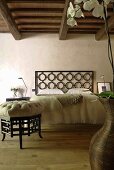 Renovated country home with rustic wooden beam ceiling - Asian style foot stool and bed with a headboard made of decorative metal grillwork