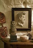 Framed half relief on a rustic stone wall and stone busts on a wooden table top