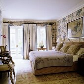 An English style bedroom with window doors, a double bed and floral patterned wall paper