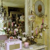 Vergoldeter Kerzenleuchter, antike Tischlampe und rosa Kofferradio vor Wandspiegel