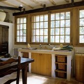 A stone kitchen counter in front of transom windows in a country house