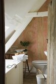 An open wooden door with a view into a partially renovated attic bathroom in an old country house