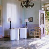 Tischlampen mit weißem Schirm auf Schreibtisch mit Mauernwinkeln im Mediterraner blaugetünchten Wohnraum mit Schachbrettmusterboden