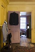 Schneiderpuppe mit Jacke im gelben Wohnraum und Blick in Arbeitsraum