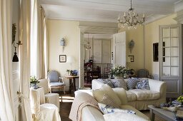 A country house-style living room with white upholstered sofas in front of open swing doors