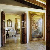 An elegant anteroom in a country house with a painted, built-in cupboard and a view through an open wooden door into a bathroom