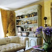 A yellow-painted living room with an antique sofa in front of a light blue bookshelf