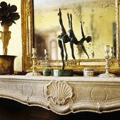 A wooden figure on a mantelpiece in front of a mirror