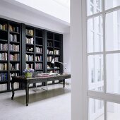 A dark grey bookshelf and an antique desk in a minimalistic room