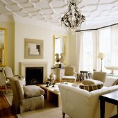 An elegant room with a fireplace, various types of seats and and chandelier hanging from the stucco ceiling