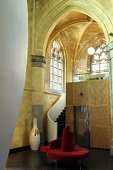 A renovated Gothic church - stairs and a built-in cubic wall with a red, circular bench