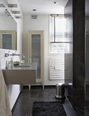 A designer bathroom with a grey tiled floor, a modern basin, a mirror and a country house-style cabinet