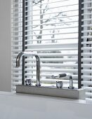 Designer bath taps in front of a window with half open blinds
