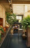 A living room in a country house with plants on the grey floor and a view of a brick wall