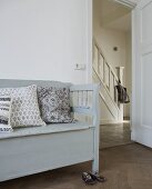 Gray bench with pillows and a view through an open door into the hallway of a country home
