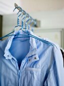 Coat hangers with a bright blue wind breaker hanging on a rack