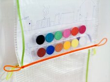 Zeichnung und bunte Wasserfarbentöpfe in Kunststoff eingeschweisst