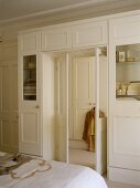 Schlafzimmer mit weißem Einbauschrank und offener Tür mit Blick in Ankleide